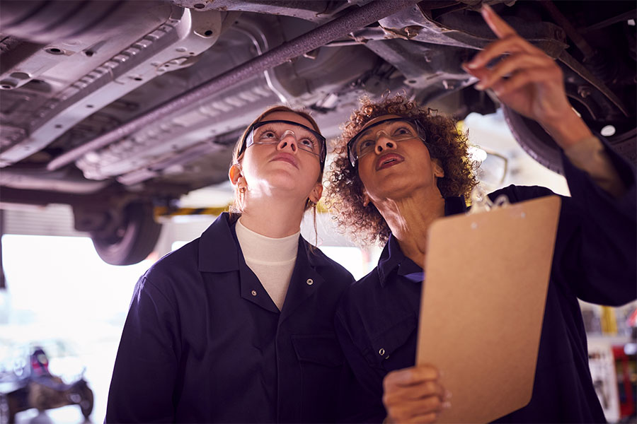 Tag and Title image of two mechanics looking at the undercarriage of a vehicle.